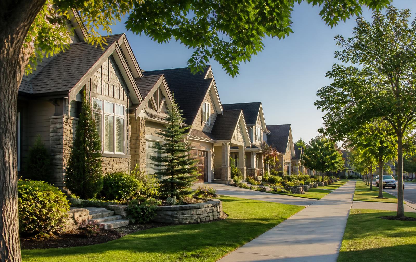 Modern suburban neighborhood street with well-maintained homes, landscaped lawns and mature trees